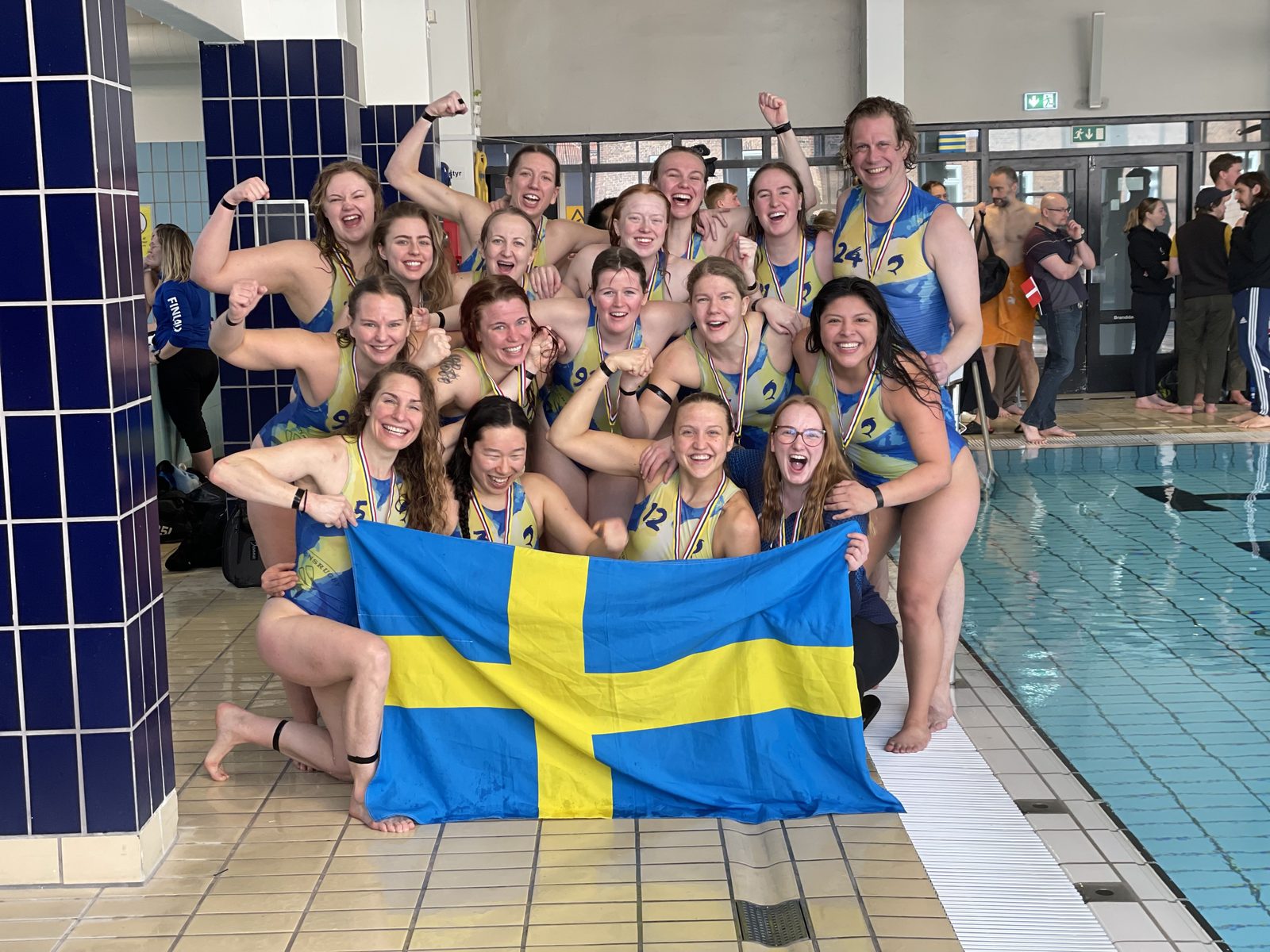 Svenska damlandslaget firar med flaggan efter NM-medalj